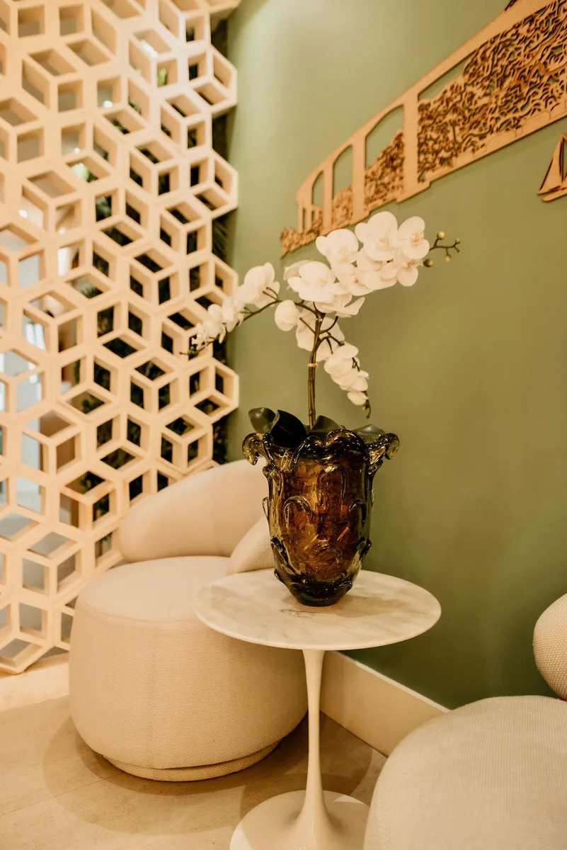 Canto de espera com poltrona, orquídea e parede verde