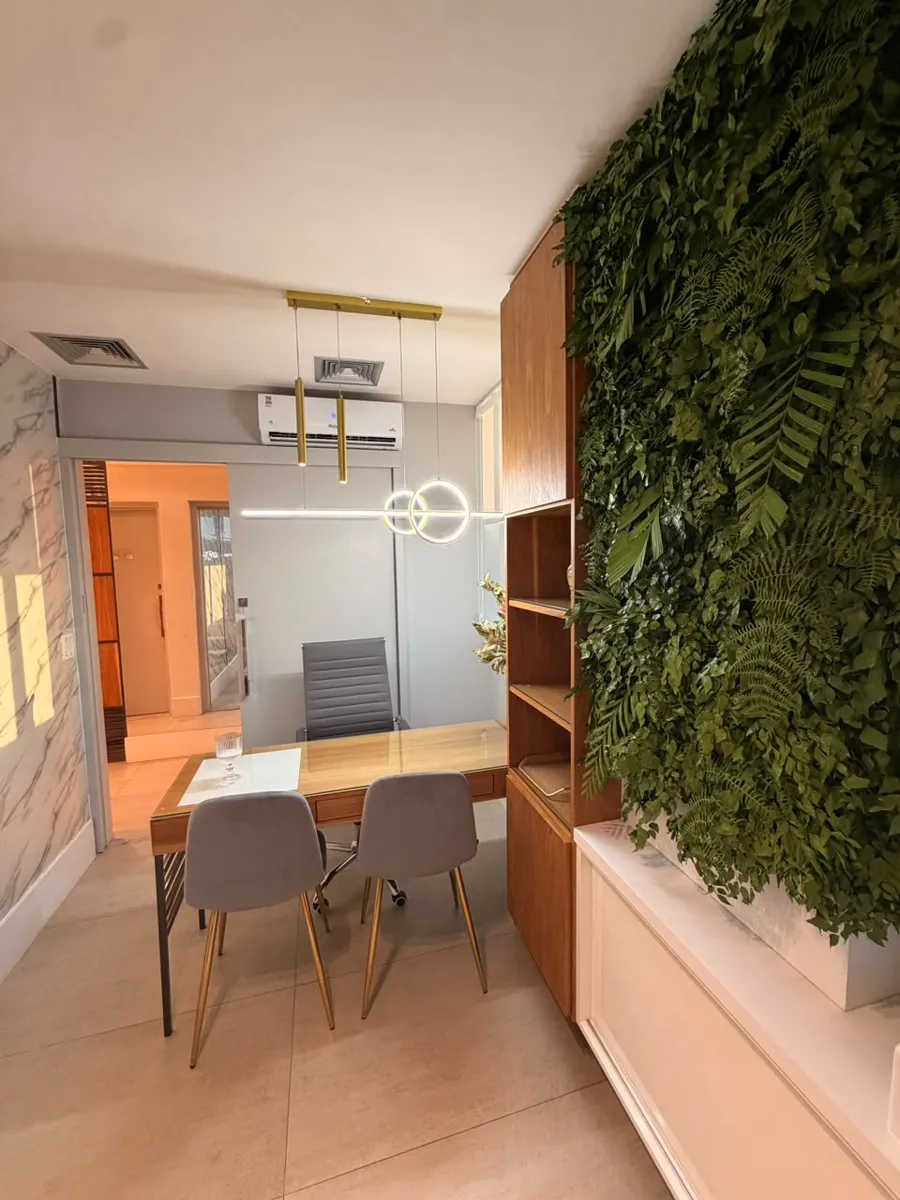 Sala 2: mesa de consulta em madeira ao lado de um jardim vertical